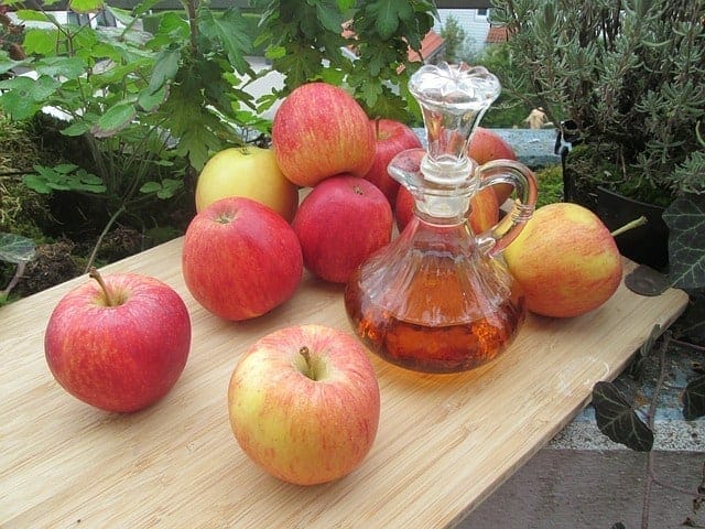 Mele fresche e una bottiglia di aceto di sidro di mele sul tavolo
