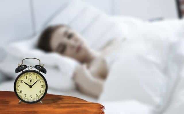  una donna addormentata con una sveglia accanto al letto