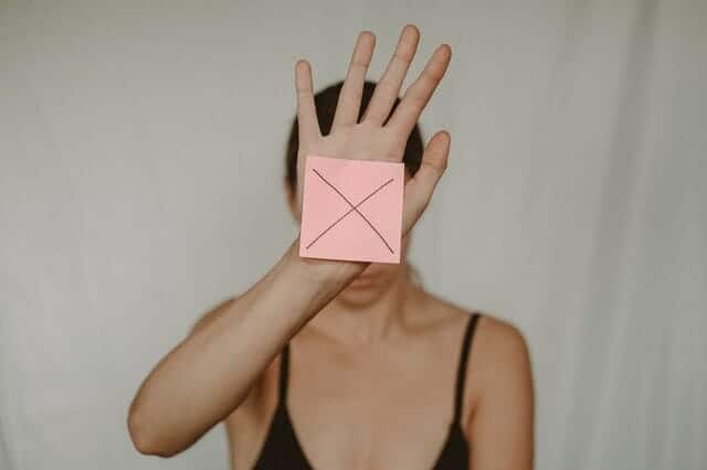  una donna triste tiene una scatola di cartone con una x davanti a sé
