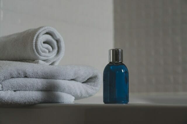  bottiglia blu con shampoo, asciugamani accanto