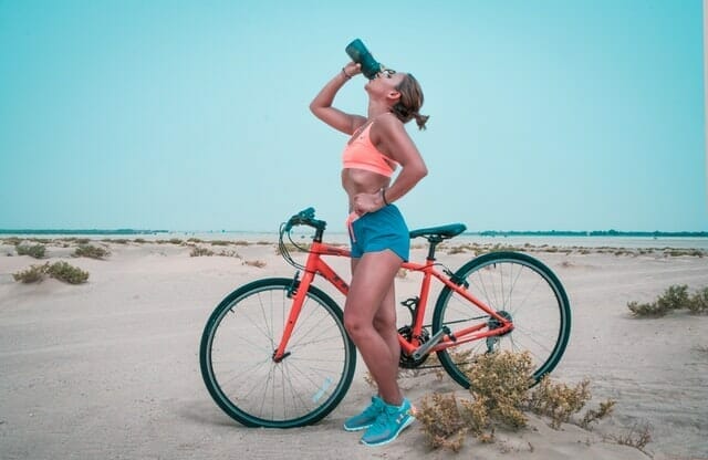  donna beve acqua da una bottiglia dopo un giro in bicicletta