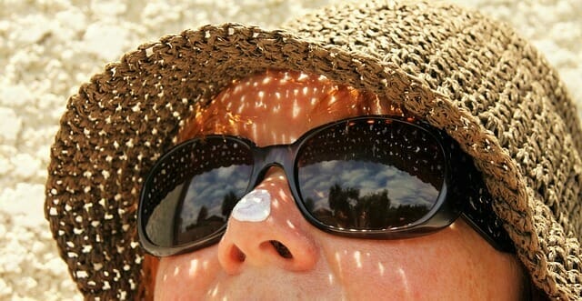  un volto di donna con occhiali da sole e un cappello