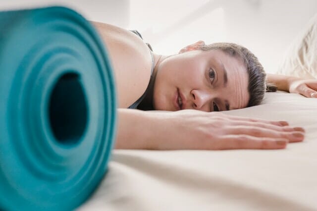  donna esausta per l'allenamento, accanto a un tappetino per gli esercizi