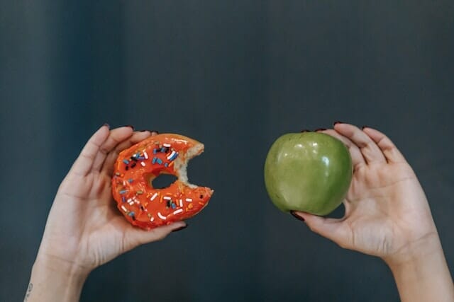  due mani, una che tiene una mela, l'altra una ciambella