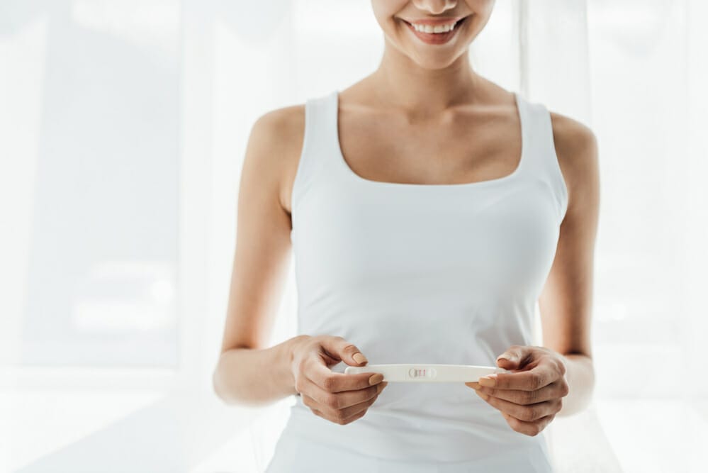  una donna soddisfatta tiene in mano un test di gravidanza positivo