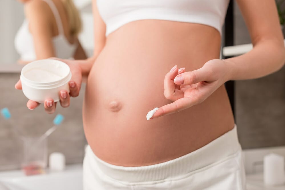  Una donna incinta lubrifica la pancia con una crema