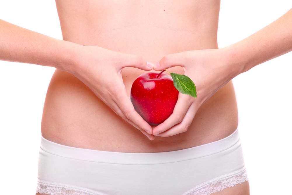  una donna tiene una mela sullo stomaco